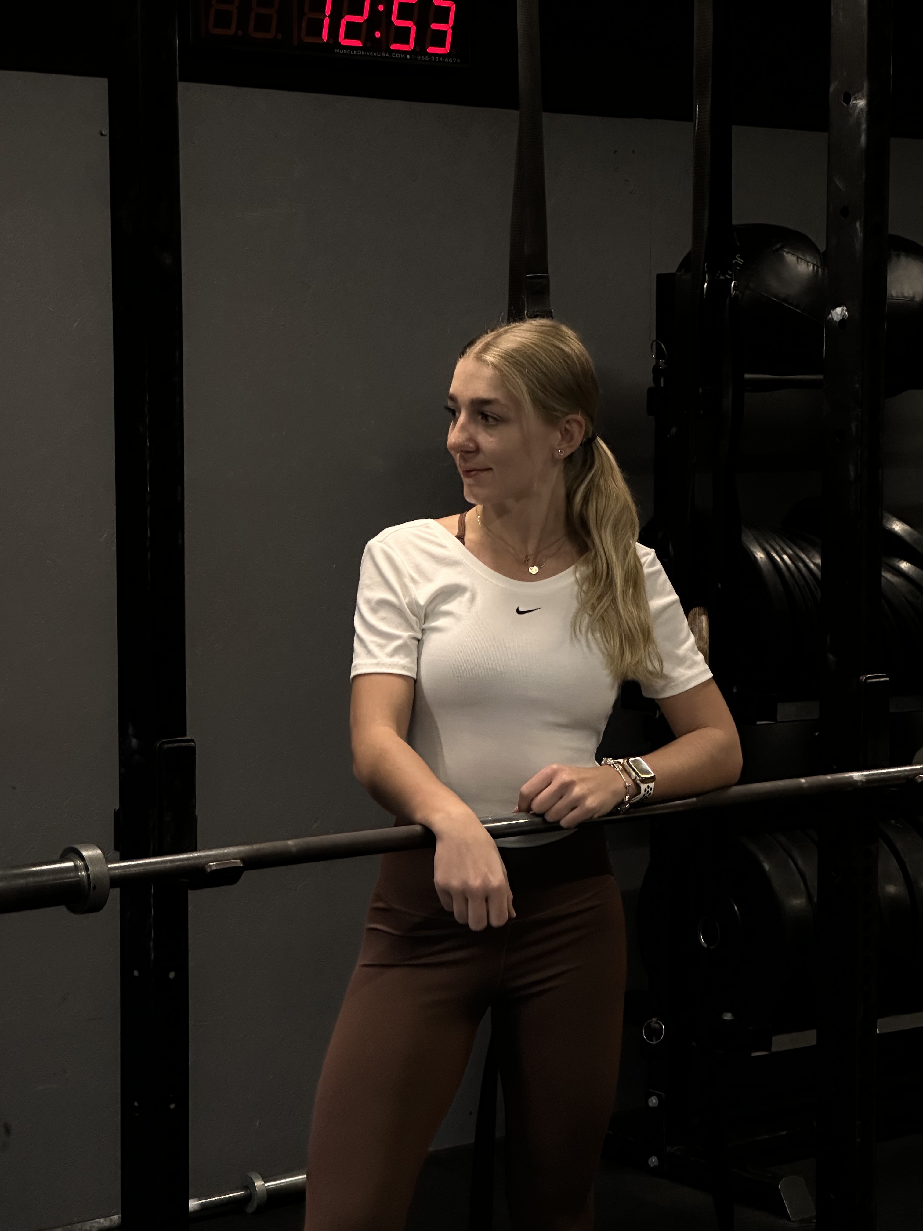 Emilia w strefie treningu siłowego, oparta o sztangę na stojaku